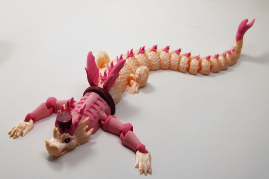 A 3D-printed articulated dragon toy in pink and peach tones, displayed on a plain light gray background.